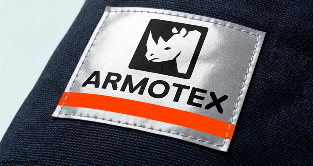 Étiquette ARMOTEX cousue sur un tissu bleu marine, avec une bande orange